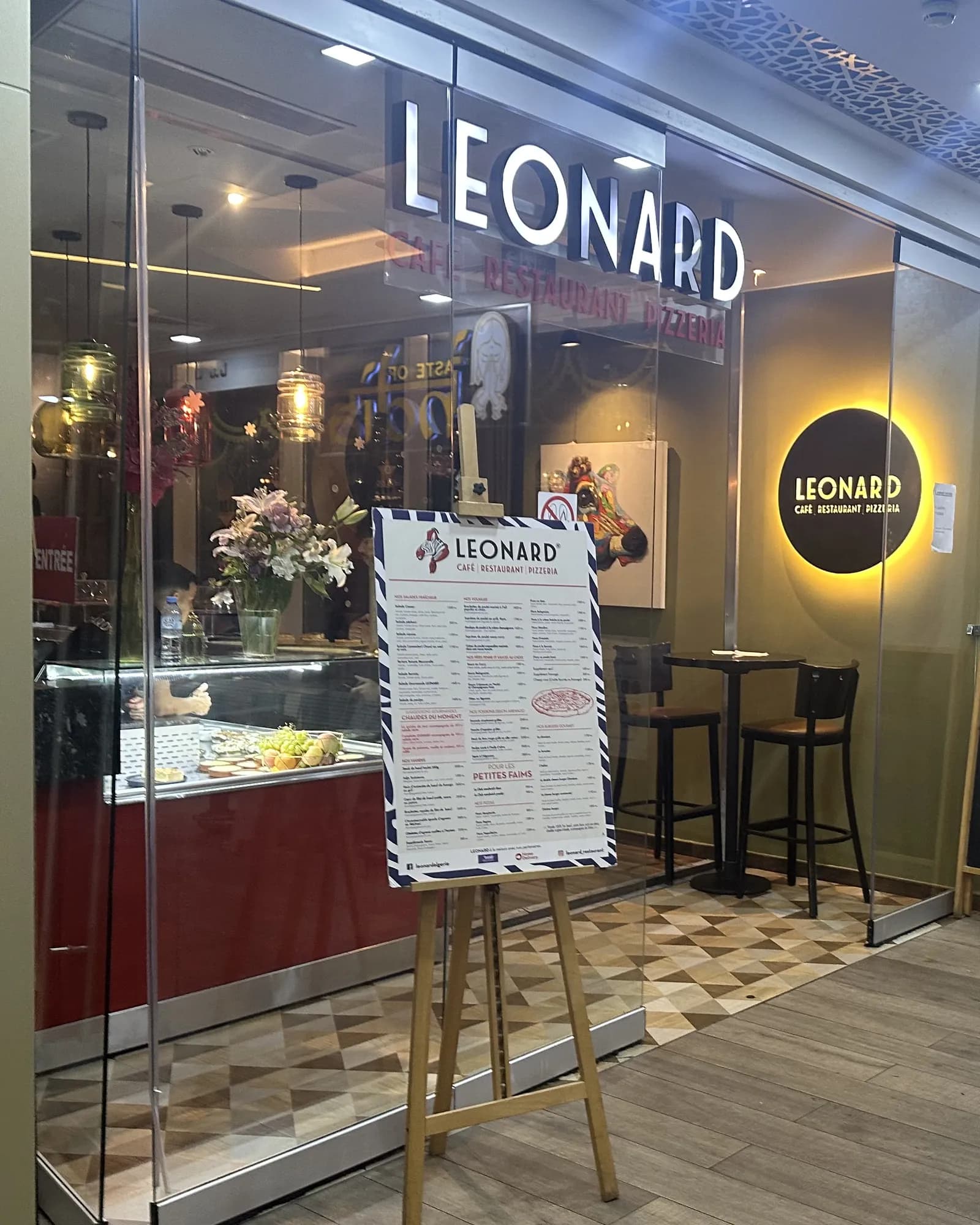 L’entrée de LEONARD au 2ᵉ étage : l’enseigne lumineuse et la carte sur son chevalet